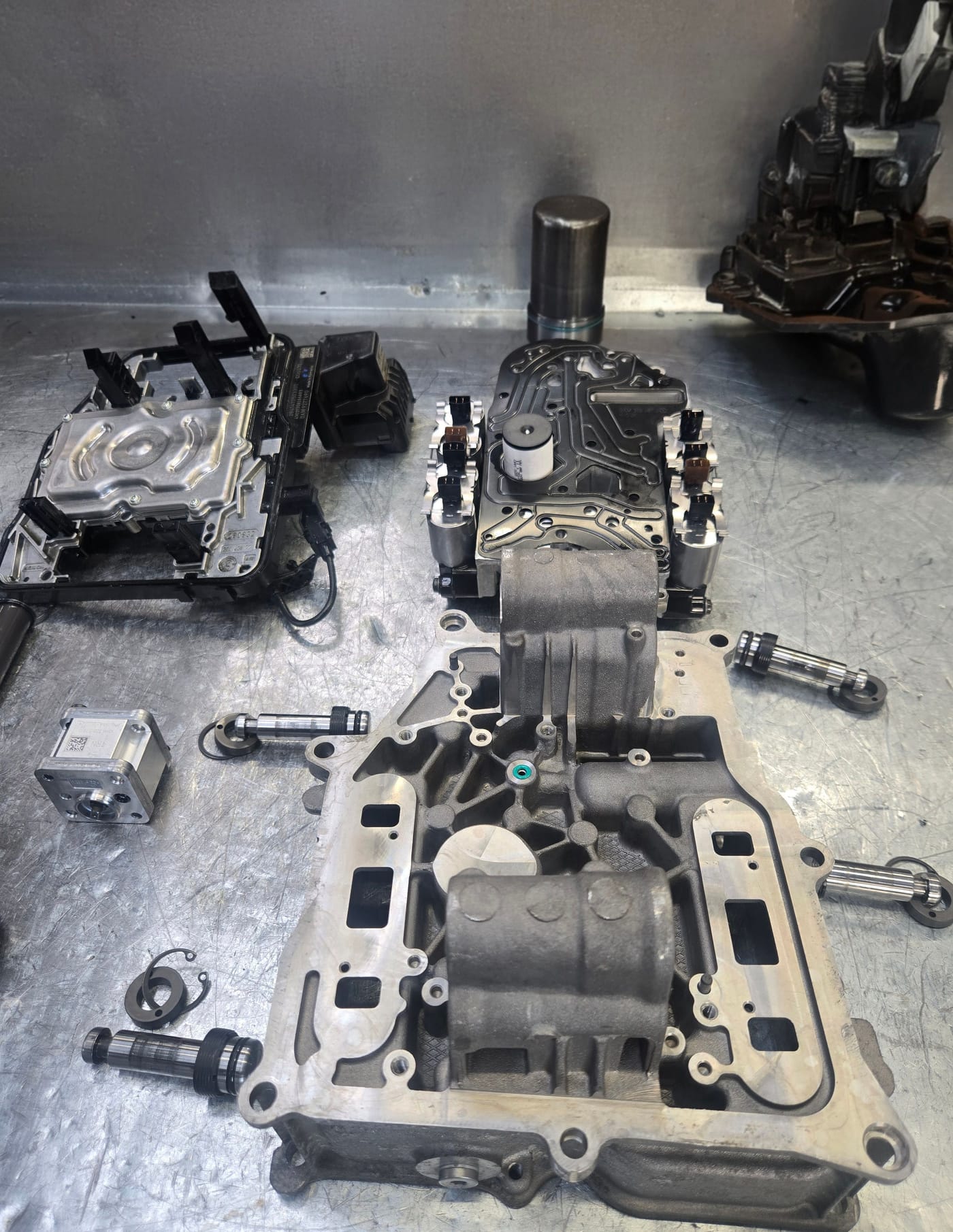 Transmission valve bodies, solenoids and separator plates laid out on the workbench during a valve body repair