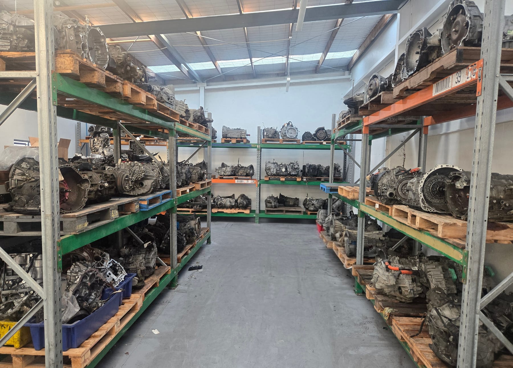 Aisle of the workshop lined with automatic transmissions on pallet racking, ready for reconditioning